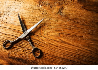 scissors sits half open on a worn butcher block counter top. vintage aged used Scissors lie on aged wooden table background. texture backdrop. empty copy space for inscription or other objects. 