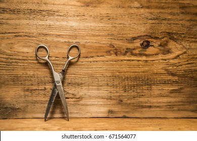 Scissors Sits Half Open On A Worn Butcher Block Counter Top. Vintage Aged Used Scissors Lie On Aged Wooden Table Background. Texture Backdrop. Empty Copy Space For Inscription Or Other Objects.