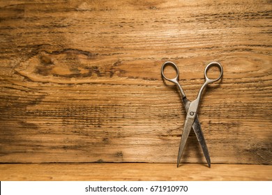 Scissors Sits Half Open On A Worn Butcher Block Counter Top. Vintage Aged Used Scissors Lie On Aged Wooden Table Background. Texture Backdrop. Empty Copy Space For Inscription Or Other Objects.