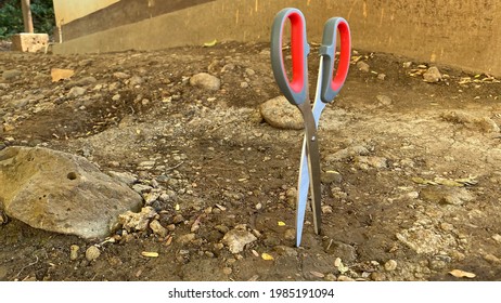 
a scissors stuck in the ground