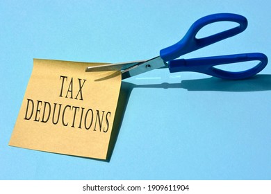 Scissors that cut yellow notepad with tax deductions text - Shutterstock ID 1909611904