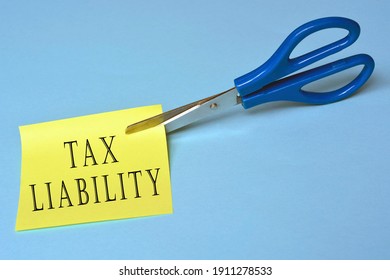 Scissors that cut yellow notepad with tax liability text on blue paper background - Shutterstock ID 1911278533