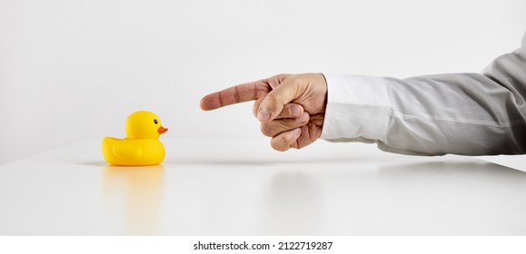 Scolding, Anger, Conflict, Complaint, Criticism, Bullying Or Peer Pressure In Business Concept. Business Person Points His Finger Towards The Rubber Duckling.