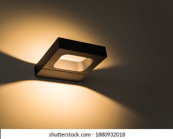 Sconce. Modern Minimalist Black Square Wall Lamp Shines With Yellow Light. Internal Lighting. Close-up. Beautiful Geometric Shadows