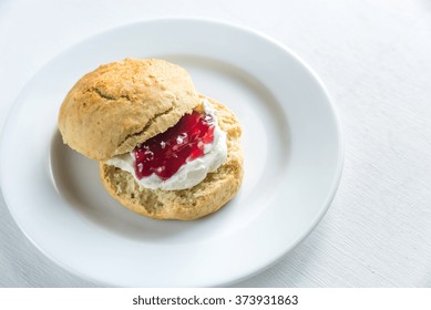 Scone With Cream And Cherry Jam On The Plate