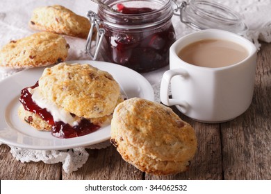 Scones with jam and tea with milk close-up on the table. horizontal