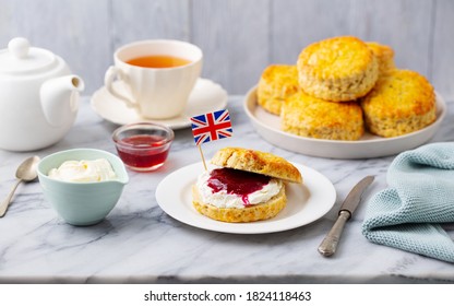Scones, tea cakes with jam, clotted cream with the flag of Great Britain. Traditional British teatime. Grey background.