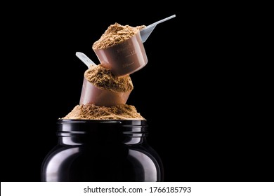 A Scoop Of Chocolate Protein Powder Drink In Black Plastic Container Isolated On Black Background With Clipping Path. Concept Of Fitness Supplement