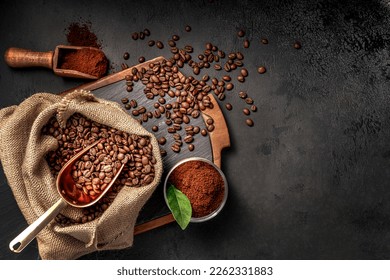 Scoop of coffee beans in a bag on dark board. Top view of ground coffee in a cup and instant coffee in a wooden cup. Place for text.