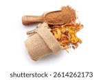 A scoop of organic Mace (Myristica fragrans) or javitri powder, along with whole mace spilled out from a jute bag. Isolated on a white background.