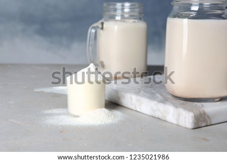 Scoop of protein powder and jar with shake on table