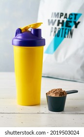 A Scoop With Protein Powder Near Shaker And Pack