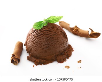 Scoop of rich creamy chocolate ice cream dessert topped with fresh mint and served with shavings