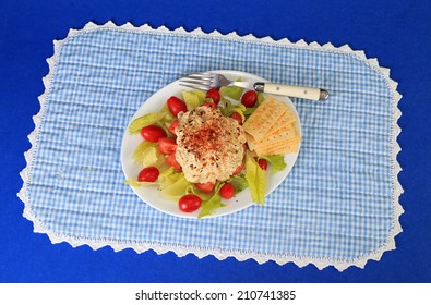 Scoop Of Tuna Salad On Romaine Lettuce With Cherry Tomatoes And Club Crackers.  White Plate On Blue And White Gingham Place Mat And Blue Background.