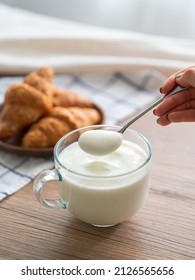 Scoop Yogurt From The Cup With A Spoon In Hand