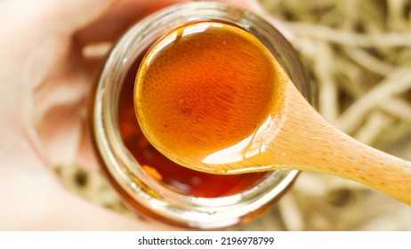 Scooping Honey Out With A Wooden Spoon. Close Up Macro Shot, Top View Flat Lay. Healthy Product Sustainable Lifestyle Concept.