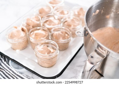 Scooping mixture into the small glass jars to make homemade chocolate ice cream. - Shutterstock ID 2254998727