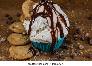 Scoops Of Chocolate Chip Cookie Dough Ice Cream In A Teal Bowl With Chocolate Chip Cookies And Chocolate Chips Scattered Around On A Dark Wood Grain Cutting Board