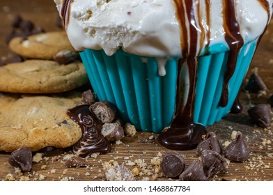 Scoops Of Chocolate Chip Cookie Dough Ice Cream In A Teal Bowl With Chocolate Chip Cookies And Chocolate Chips Scattered Around On A Dark Wood Grain Cutting Board