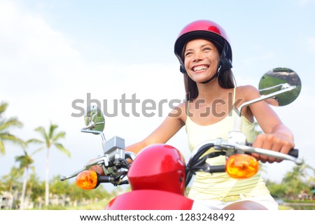 Scooter driving girl riding across town on motorcycle transport. Happy Asian woman traveling road trip on moped. Summer travel.
