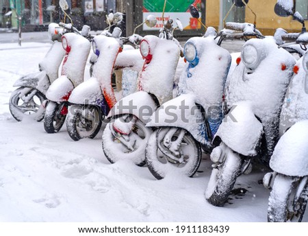 Scooters in the parking lot covered in snow