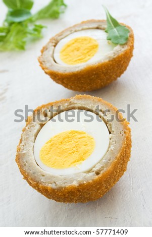 Scotch egg on a white board with green salad
