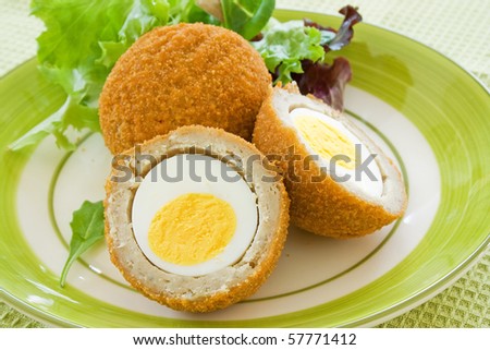 Scotch eggs on a plate with a green salad