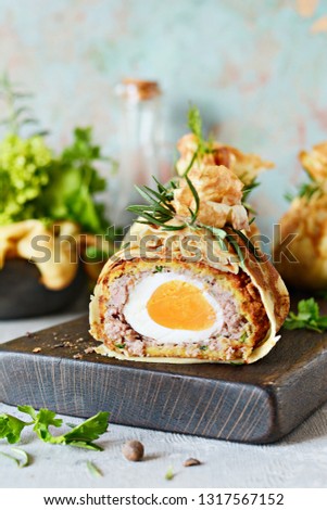 Scotch eggs in a pancake bag with greens on a gray-blue background. A classic dish in an unconventional serving. Delicious and appetizing dish of British cuisine.