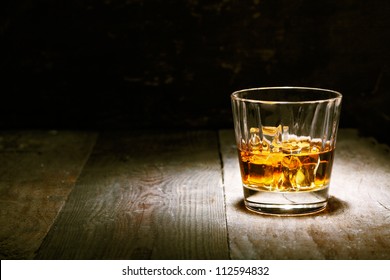 Scotch on wooden background with copyspace. An old and vintage countertop with highlight and a glass of hard liquor - Powered by Shutterstock