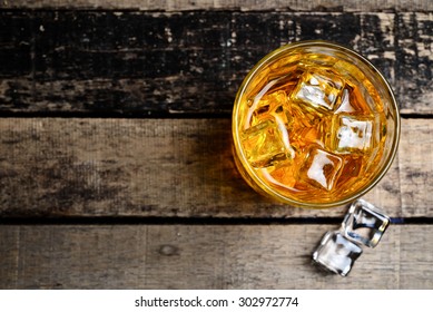 Scotch On Wooden Background With Copyspace. An Old And Vintage Countertop With Highlight And A Glass Of Hard Liquor 