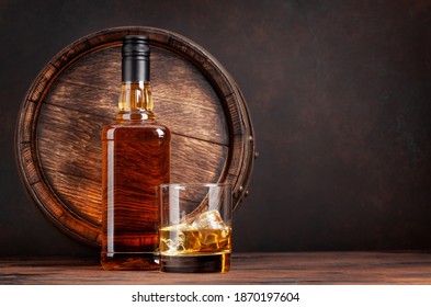 Scotch whiskey bottle, glass and old wooden barrel. With copy space