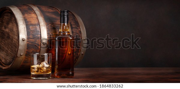 Scotch whiskey bottle, glass and old wooden barrel.\
With copy space