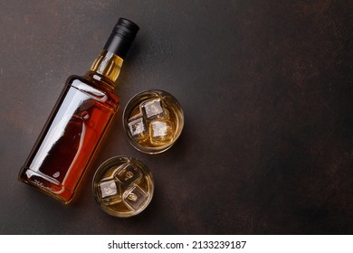 Botella de whisky escocés y gafas sobre mesa de piedra. Con espacio de copia. Vista plana superior