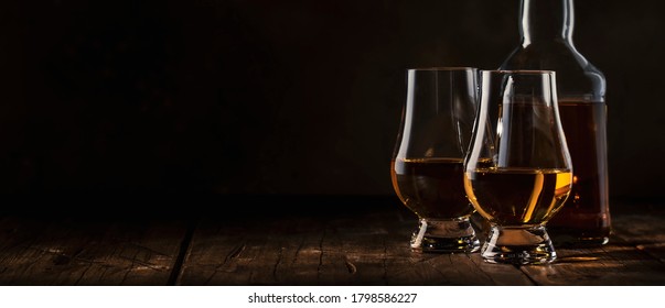 Scotch Whiskey without ice in glasses and bottle, rustic wood background, copy space banner 