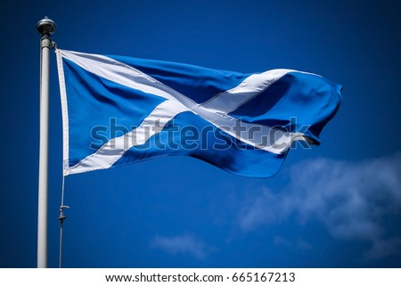 Scotland flag flying in sunshine against blue sky