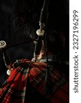 Scottish bagpiper in traditional red and black tartan dress, Edinburgh, scotland