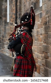 Scottish Piper Playing The Bagpipes In Traditional Costume In Edinburgh