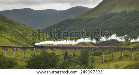 Scottish steam train passing a classic bridge. Horizontal