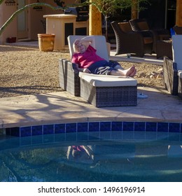 Scottsdale, Arizona / USA- February 11, 2016:  Senior Female Lounges Next To Swimming Pool In Arid Southwest.