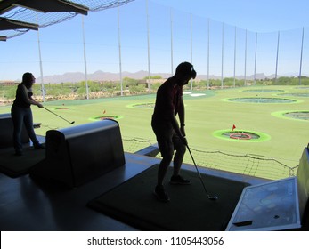 Scottsdale, Arizona / USA - May 20 2018: Silhouettes of people playing at TopGolf with targets in the background and blue sky 