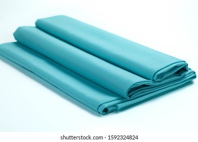 The Scouring Of Cotton Fabric  With Satin Effect Of Blue Color Is Beautifully Laid In A Roll On A White Isolated Background