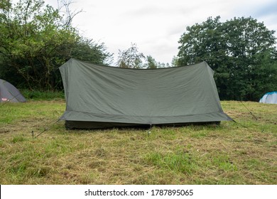 Scout Camping. Army Military Tent Close Up In The Base Camp. Lots Of  Tents Stand On A Field Against A Green Forest. 