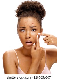Scowling girl in shock of her acne. Photo of african american girl with problem skin on white background. Skin care concept
