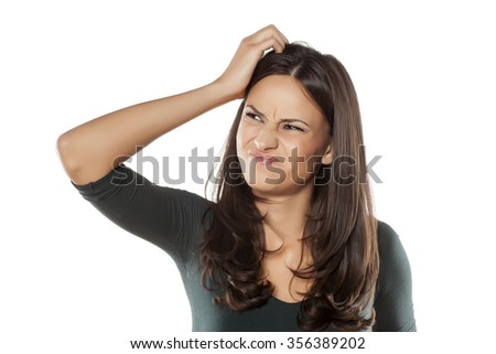scowling young woman scratching her head
