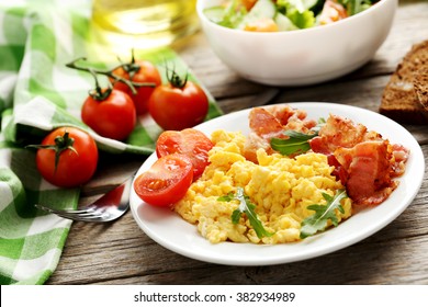 Scrambled Eggs With Bacon And Vegetables On A Grey Wooden Table