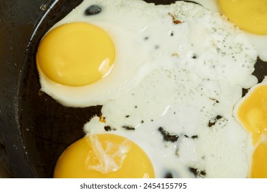 Scrambled eggs are fried in a frying pan in oil close-up. Horizontal photo