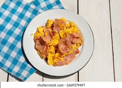 Scrambled eggs with ham for breakfast on white background
