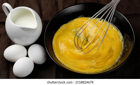 Scrambled eggs, omelette. Сhef whisking eggs in black bowl cooking omelette with milk. Traditional heathy breakfast - Powered by Shutterstock