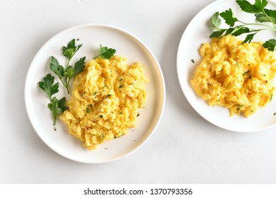 Scrambled eggs on plate over white stone background. Top view, flat lay