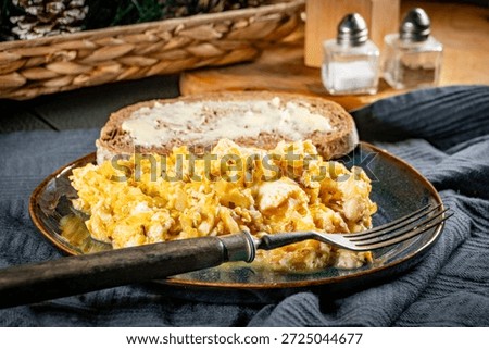 Scrambled eggs with onion served with bread on a blue plate.